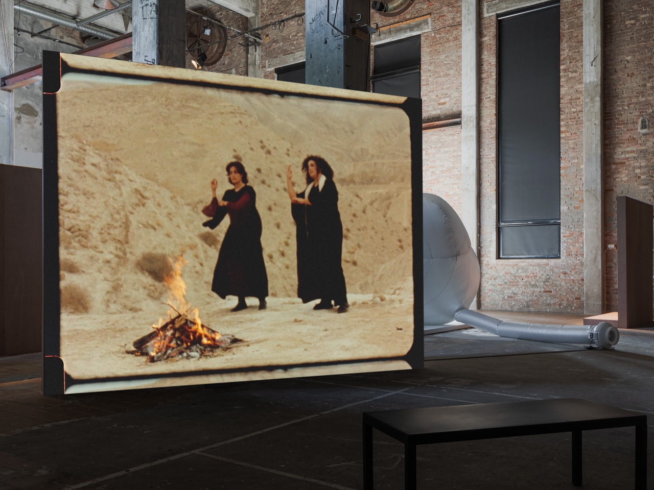 Video projection of women in front of fire in the desert