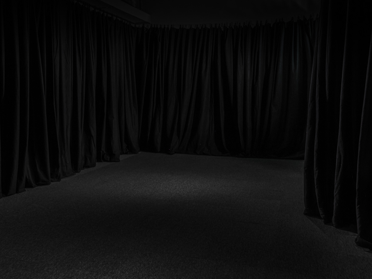 Dark lit room with black drapes on the walls