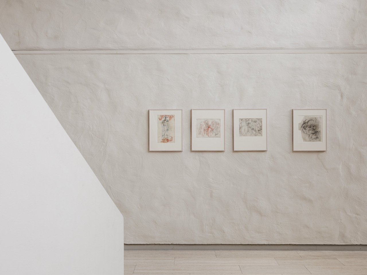 Four framed artworks on a a white stone wall