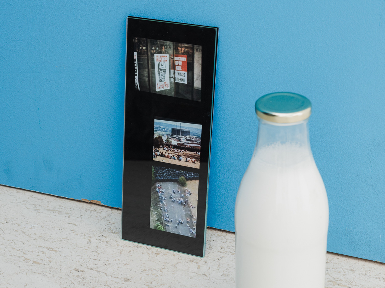 Bottle of milk and photograph in front of blue wall