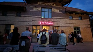 människor utanför ett upplyst stationshus